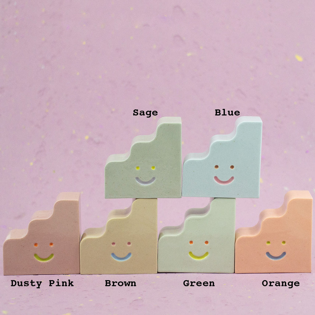Set of colorful ceramic figurines with smiley faces on a pink background