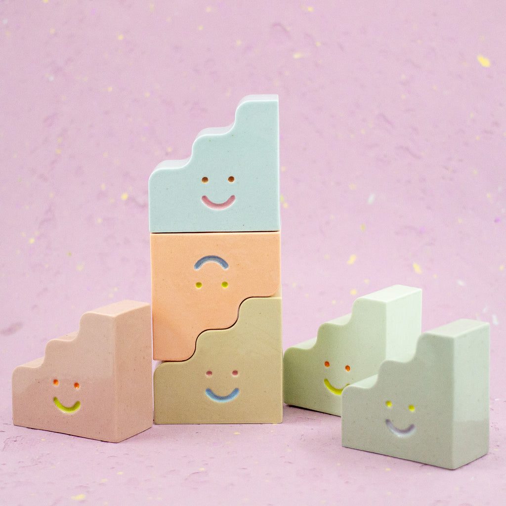 Set of colorful ceramic figurines with smiley faces on a pink background