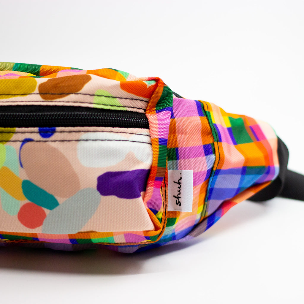 Colorful patterned fanny pack with a brand label on a white background