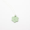 Necklace with a green flower-shaped pendant on a white background