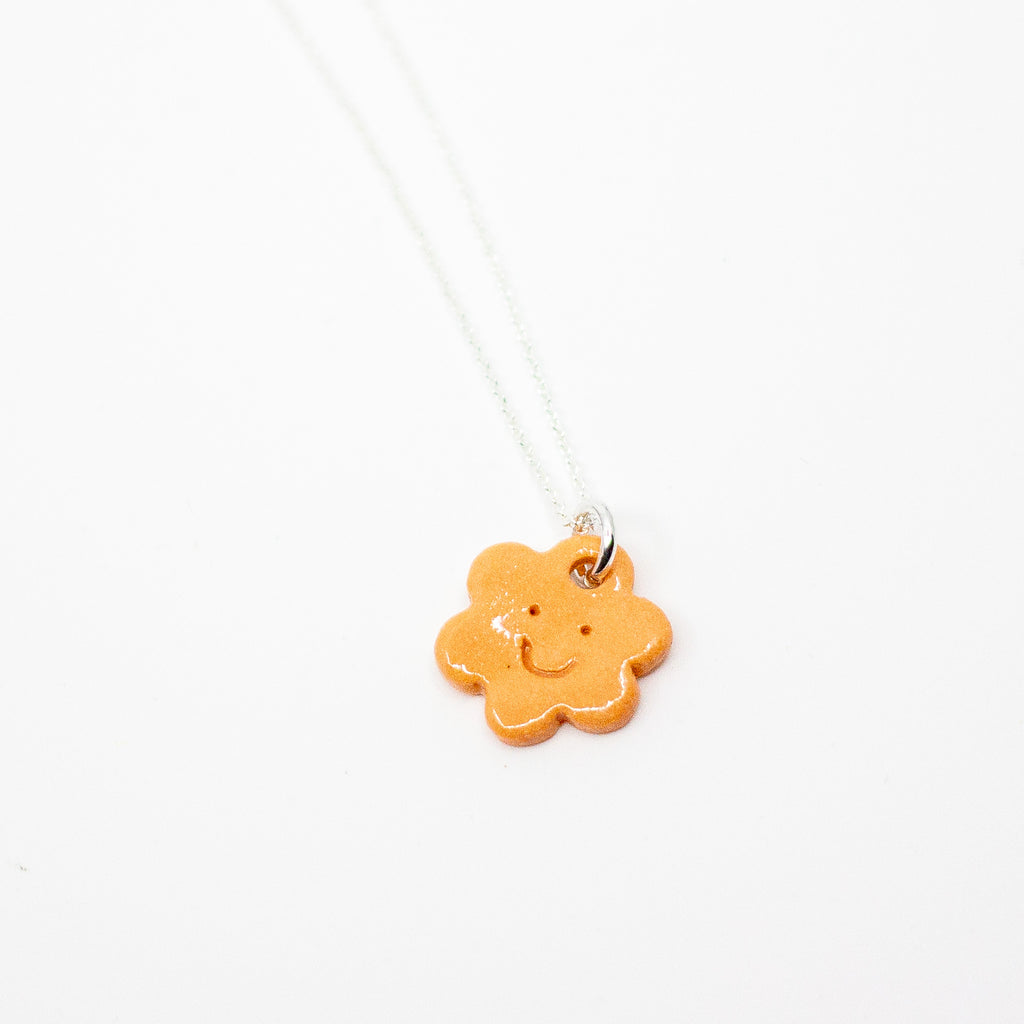 Orange flower-shaped pendant on a silver chain against a white background