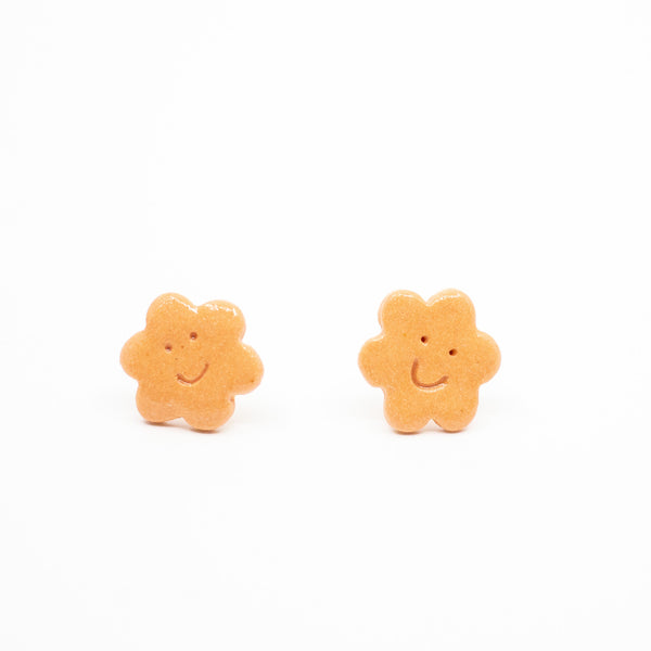 Two orange flower-shaped earrings on a white background