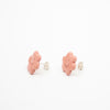 Pair of pink flower shaped earrings with smiley faces on a white background