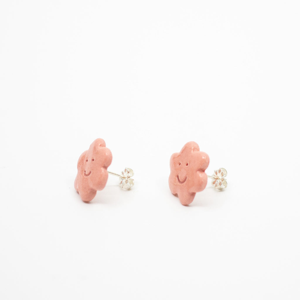 Pair of pink flower shaped earrings with smiley faces on a white background