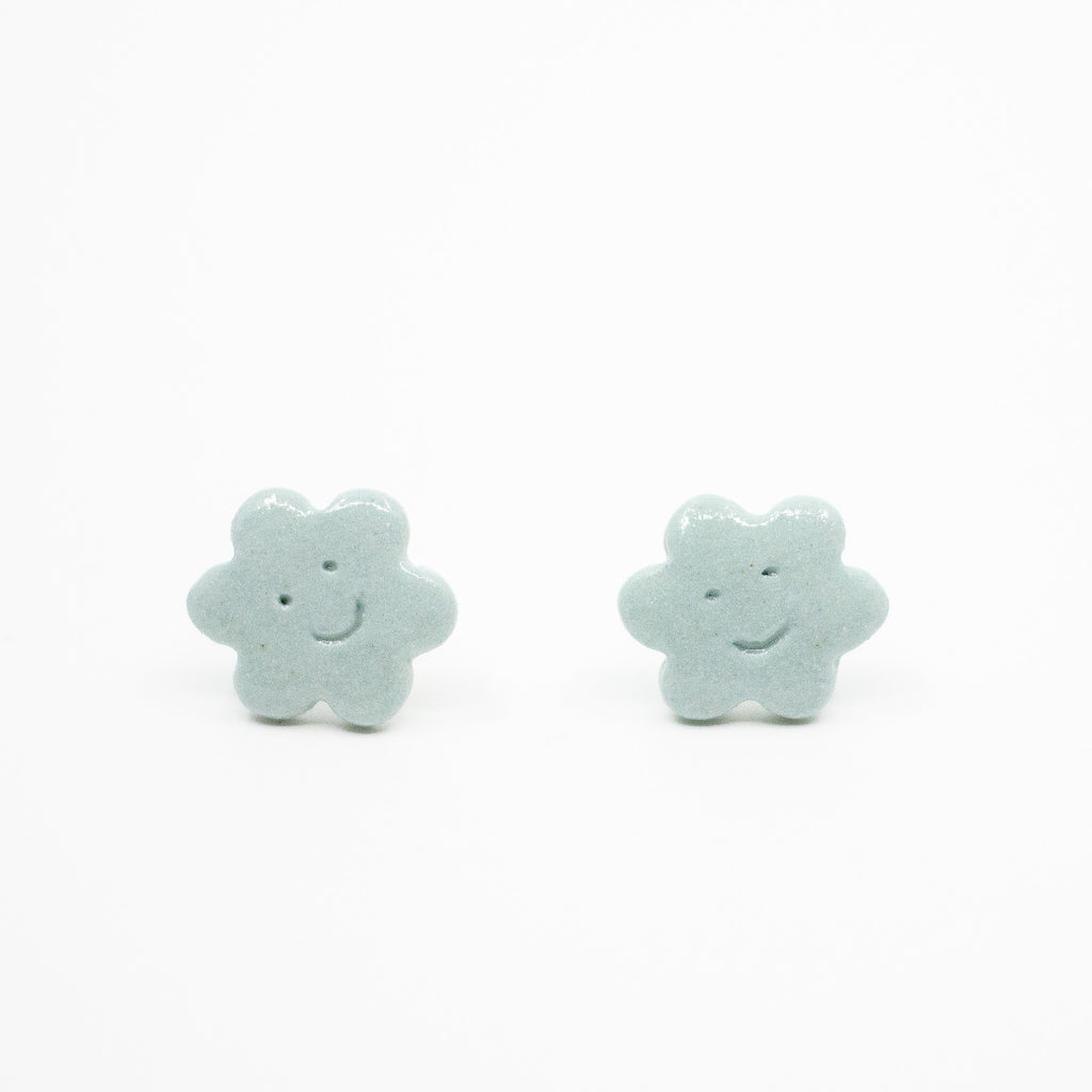 Pair of light blue flower-shaped earrings on a white background
