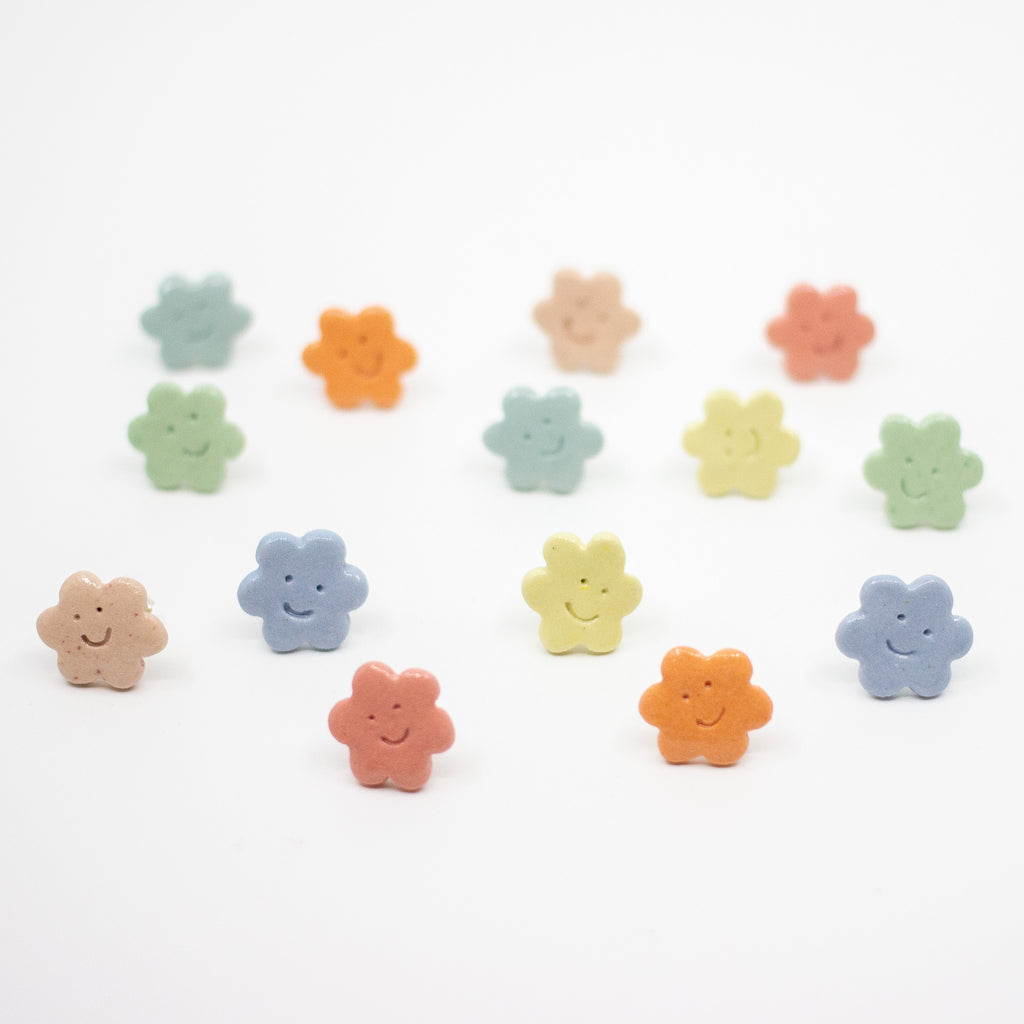 Set of colorful flower-shaped earrings on a white background