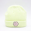 Front view of a Lime wide knit beanie with a folded brim, featuring a smiling embroidered flower patch on the front, displayed against a plain white background.