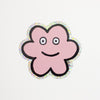 A die-cut sticker featuring a cute flower shaped character with a holographic border, set against a plain white background.