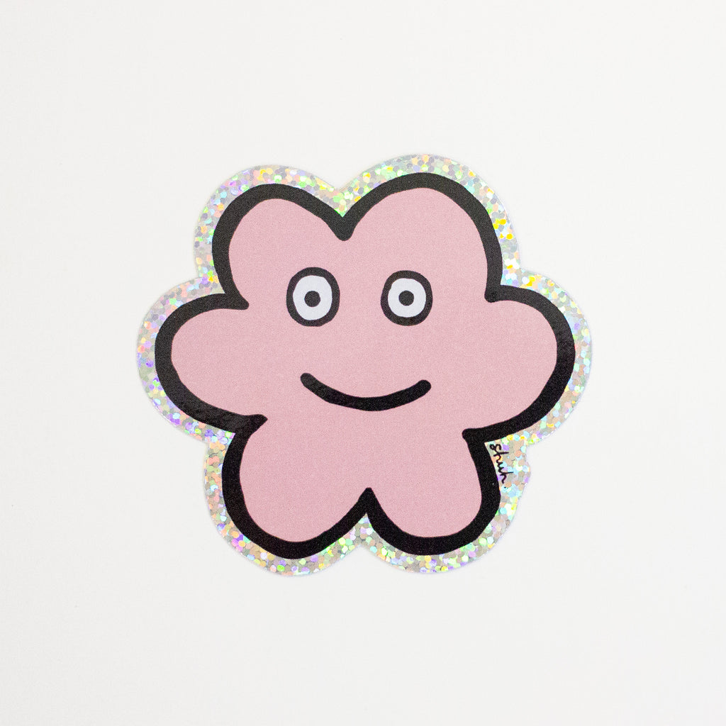 A die-cut sticker featuring a cute flower shaped character with a holographic border, set against a plain white background.