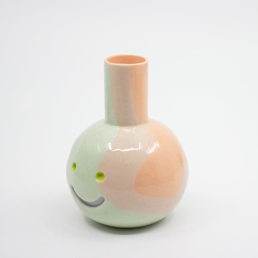 Ceramic vase with a smiley face design on a white background