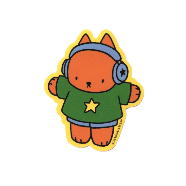 A cartoon-style die-cut sticker featuring an orange cat wearing blue headphones, a green shirt with a yellow star, and blue shorts, outlined in yellow, on a plain white background.