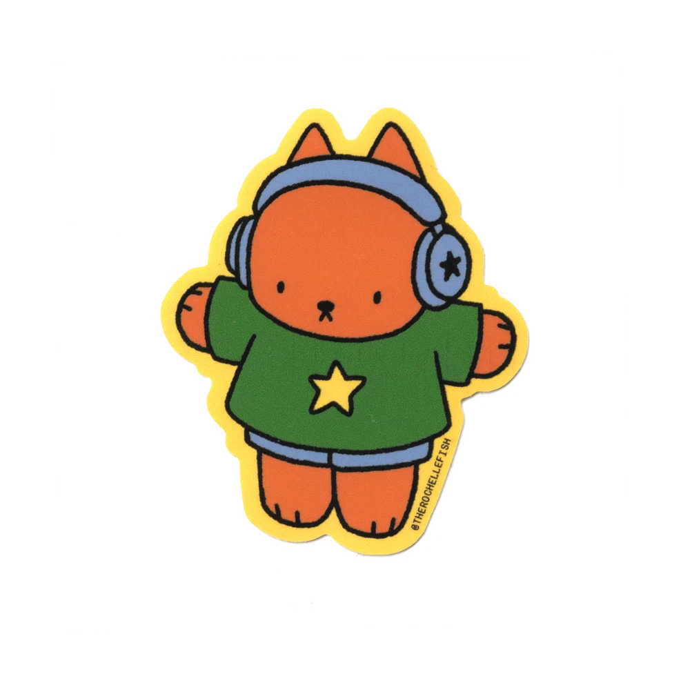 A cartoon-style die-cut sticker featuring an orange cat wearing blue headphones, a green shirt with a yellow star, and blue shorts, outlined in yellow, on a plain white background.