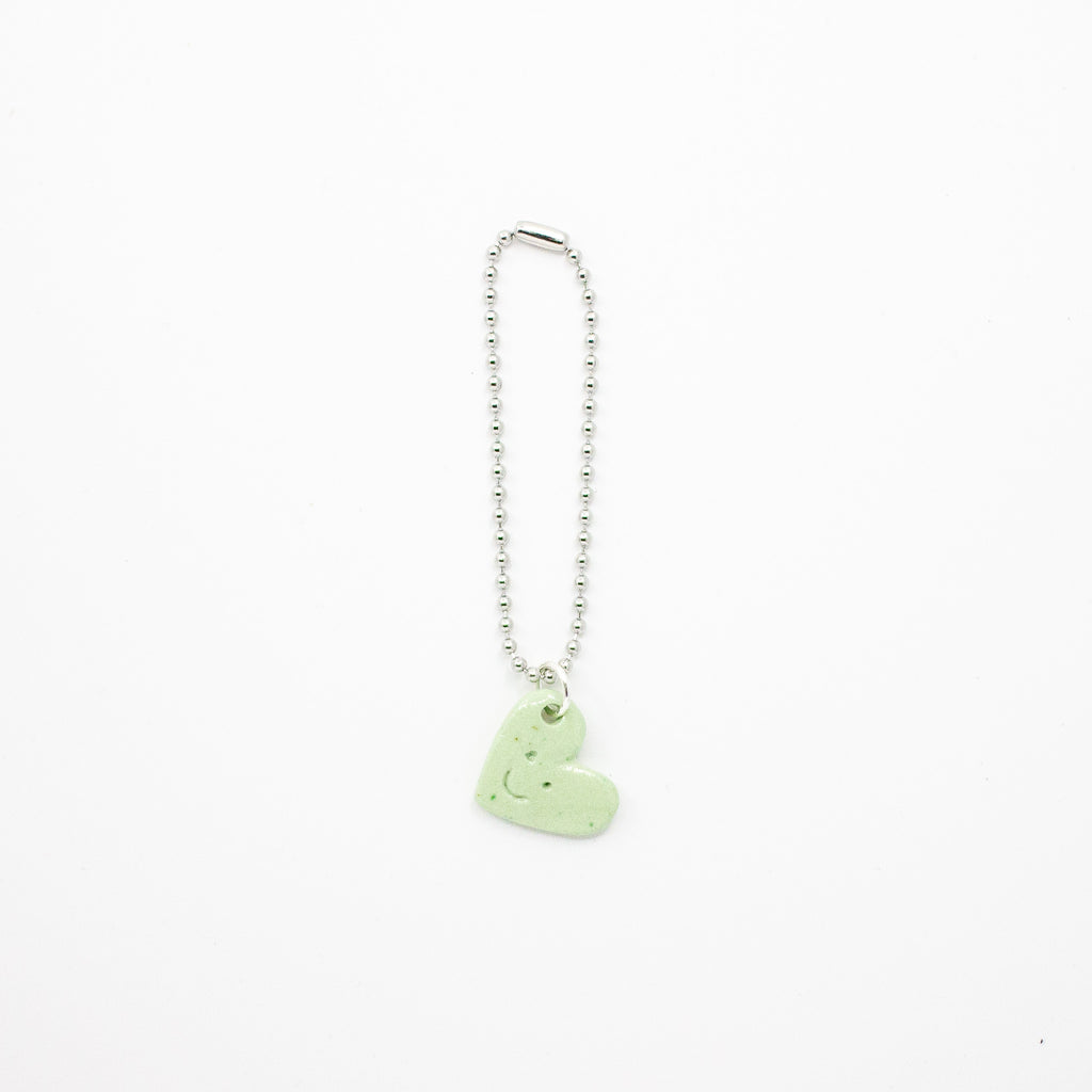 Keychain with a green heart-shaped charm on a white background