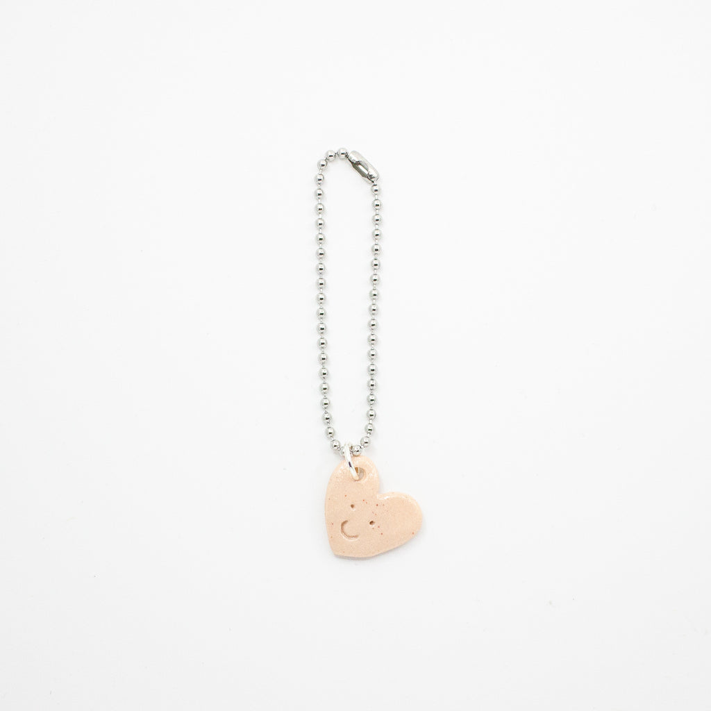 Heart-shaped charm on a chain against a white background