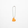 Orange heart-shaped charm with a metal chain on a white background