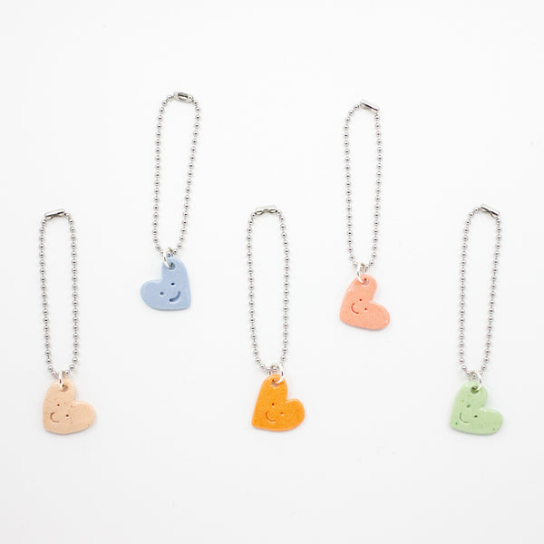 Set of five bag charms with heart-shaped pendants in blue, orange, pink, and green on a white background.