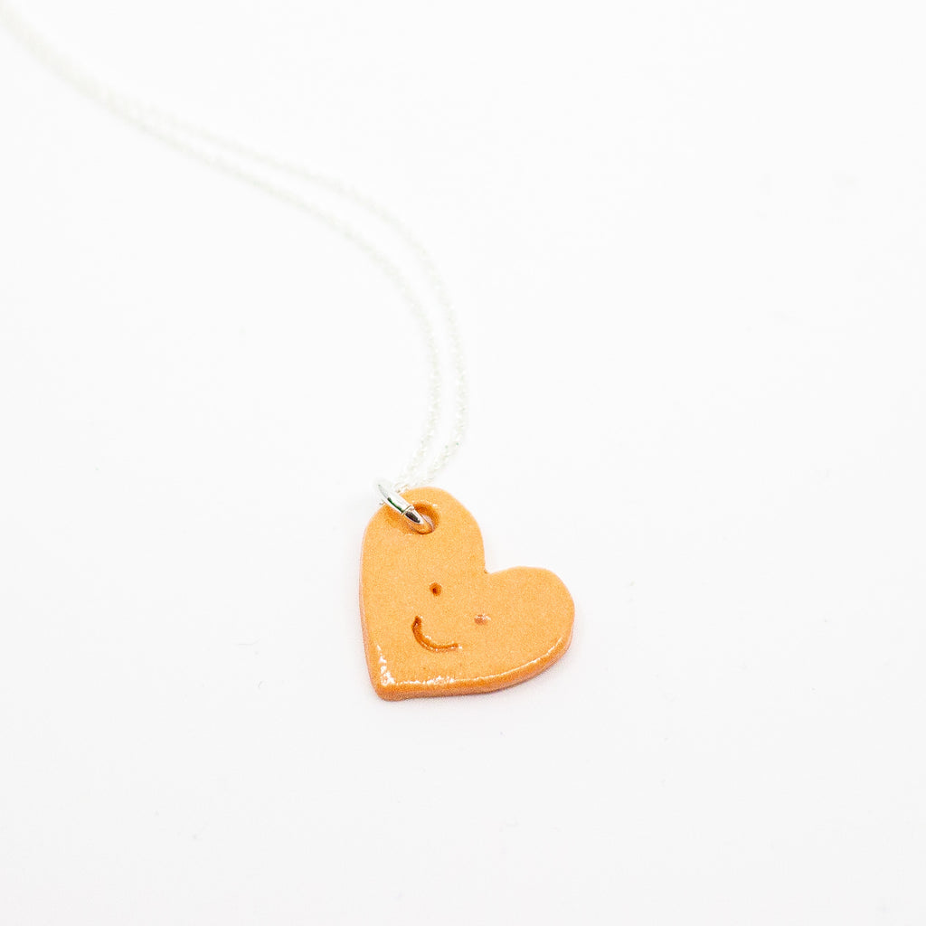 Heart-shaped pendant with a smiley face on a white background