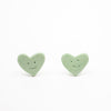 Two green heart-shaped smiley face objects on a white background