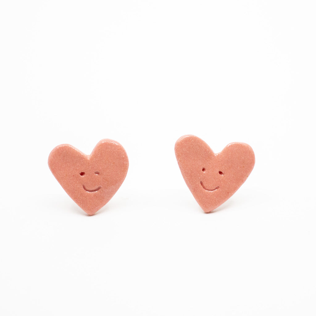 Heart-shaped earrings with smiley faces on a white background