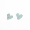 Two sky blue heart-shaped earrings with smiling faces on a white background