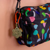 Black bag with colorful patterns and a keychain on a beige background