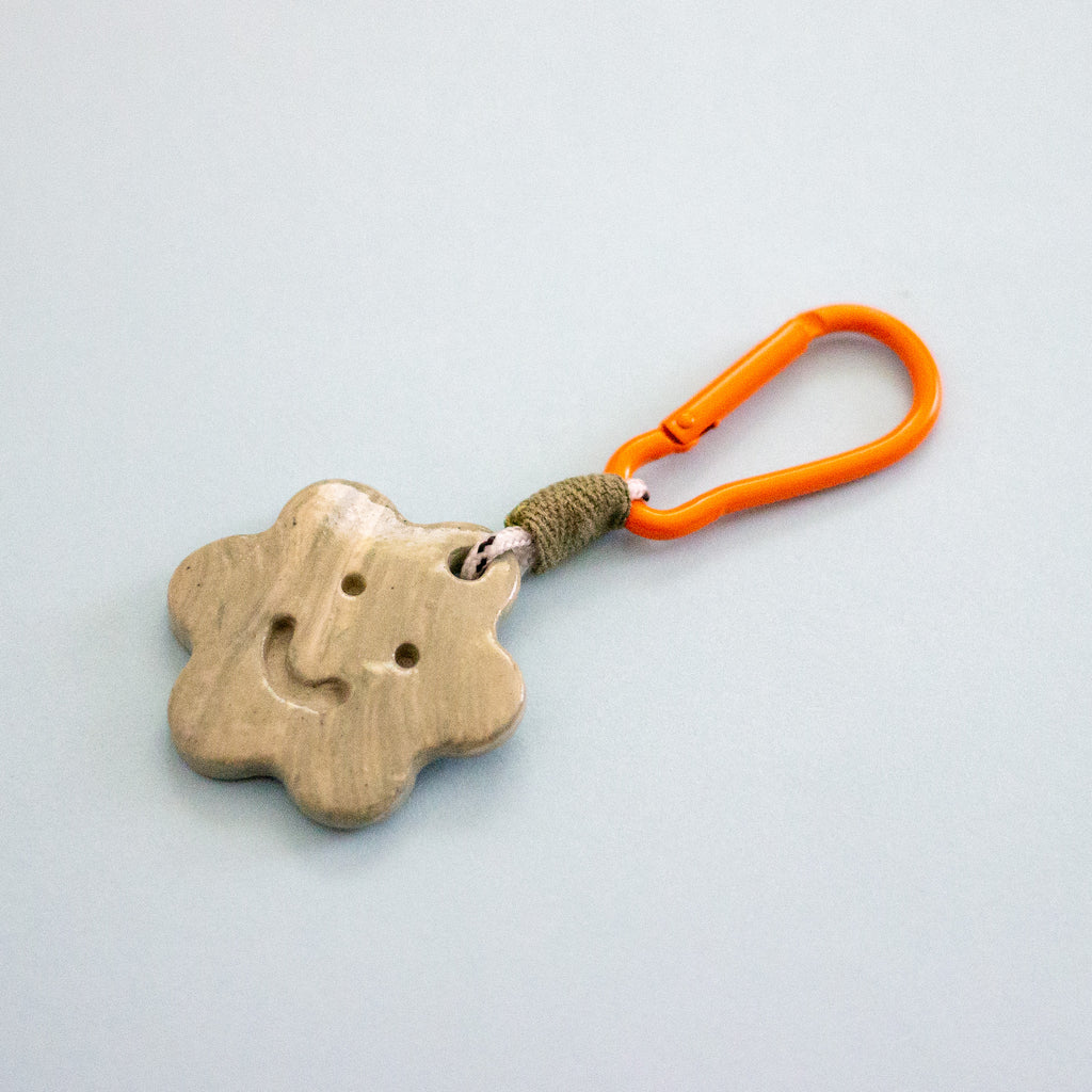 Keychain with a ceramic charm and orange carabiner on a light gray background