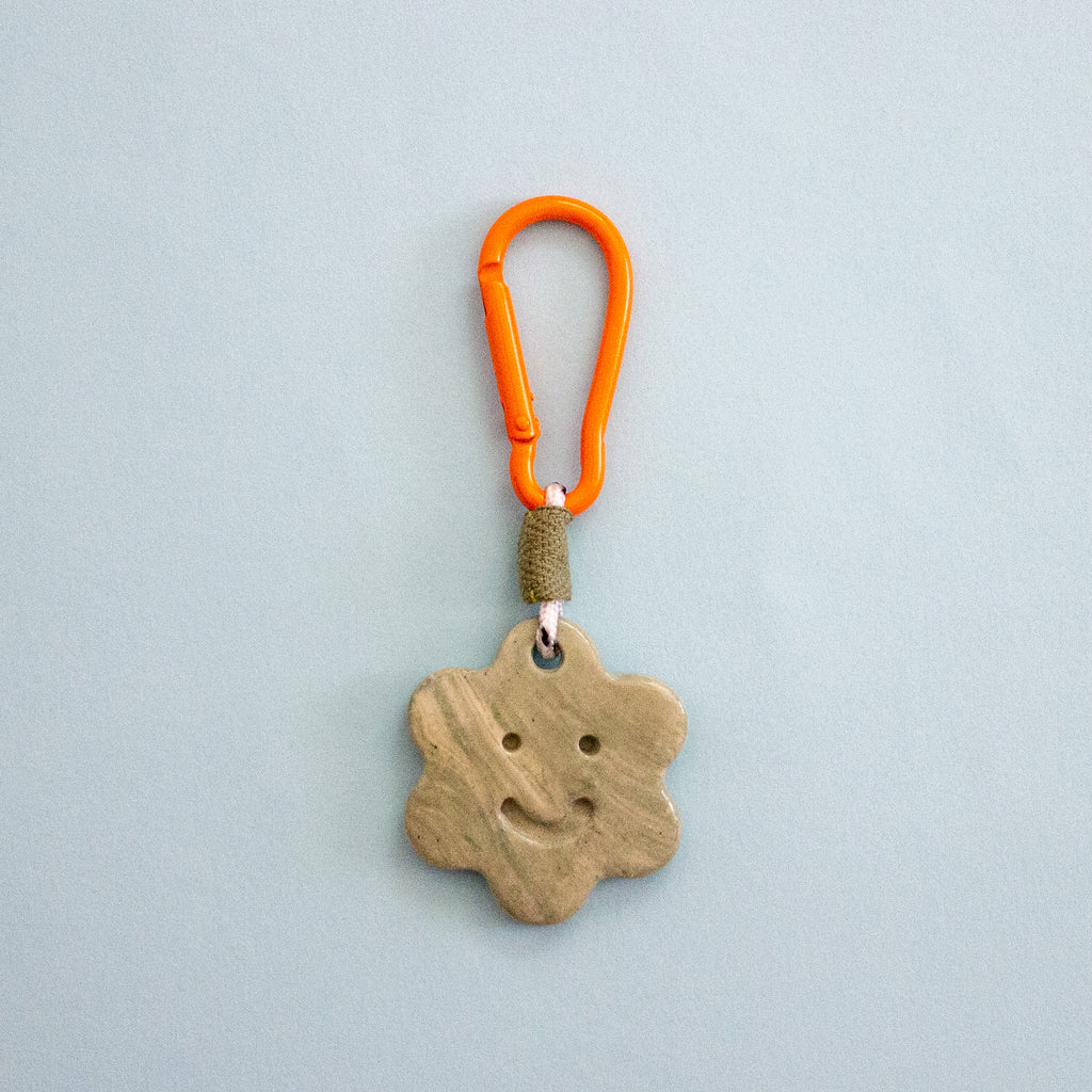 Keychain with star-shaped ceramic charm and orange carabiner on a light blue background