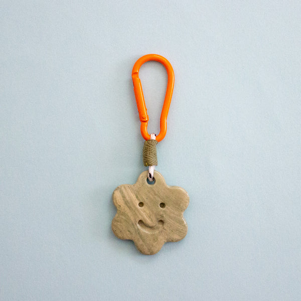 Keychain with star-shaped ceramic charm and orange carabiner on a light blue background