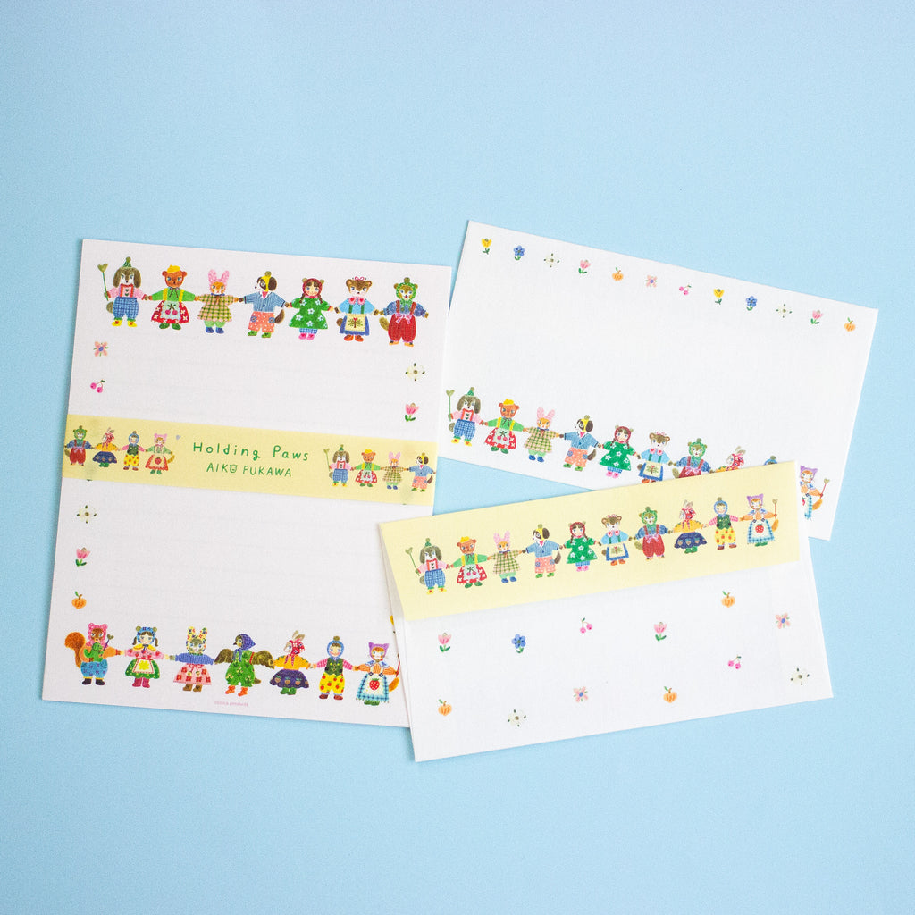 A set of letterset consisting of a writing sheet and envelopes featuring colourful cartoon animal characters along the borders. The items are arranged on a light blue background.