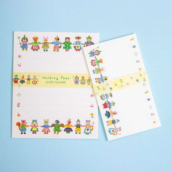 A set of white stationery items featuring colourful cartoon animal characters along the borders, with a pale yellow band across the center. The items are arranged on a light blue background.