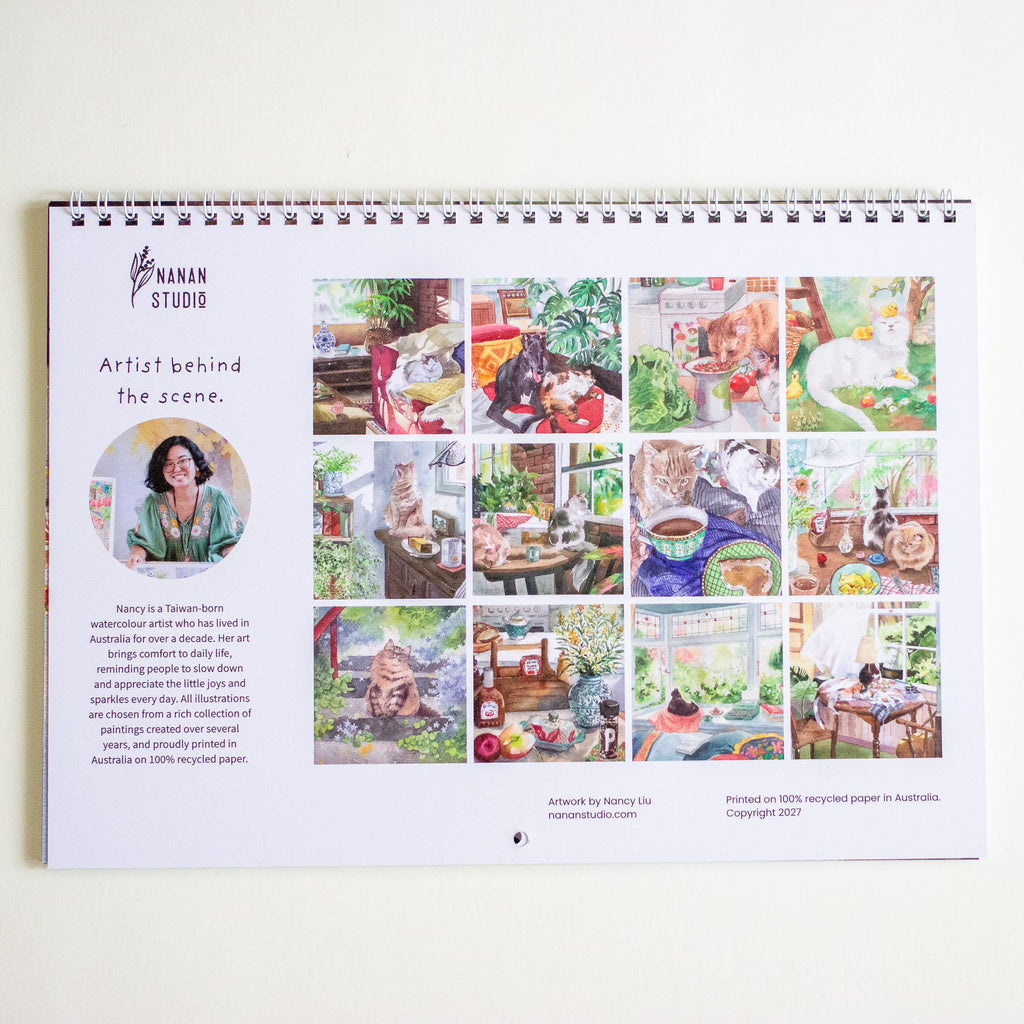 A spiral-bound calendar from Nanan Studio is shown against a plain white wall. The page features a portrait photo of a woman, the text 'Artist behind the scene,' and a grid of colourful illustrated artworks.