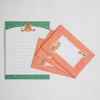 A set of cute stationery letterset featuring a teddy bear illustration. One flat white letter sheet with green borders is shown next to three coral-orange memo envelopes with white writing areas, all arranged on a light grey background.