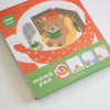 A Memo Pad notepad featuring a cute illustration of a teddy bear reading a green book in a cosy scene. The memo pad has a green bottom section with the text 'memo pad' and small preview area, and a red-orange top section indicating '100 sheets'.