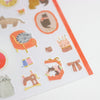 A close-up of a sheet of cute cat-themed stickers on a white background, featuring illustrations of cats, an orange armchair, a sewing machine, and small accessories.
