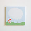 A square notepad with a whimsical illustration of a small house on a green hill under a large blank speech bubble, set against a plain white background.