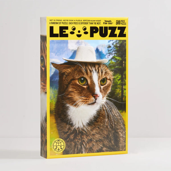 A 500-piece jigsaw puzzle box by Le Puzz featuring a close-up photo of a tabby and white cat wearing a white hat, set against a yellow border on a light grey background.