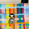 Colorful fabric background with a black and white character pin.