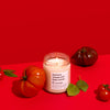 Candle with tomatoes and leaves on a red background