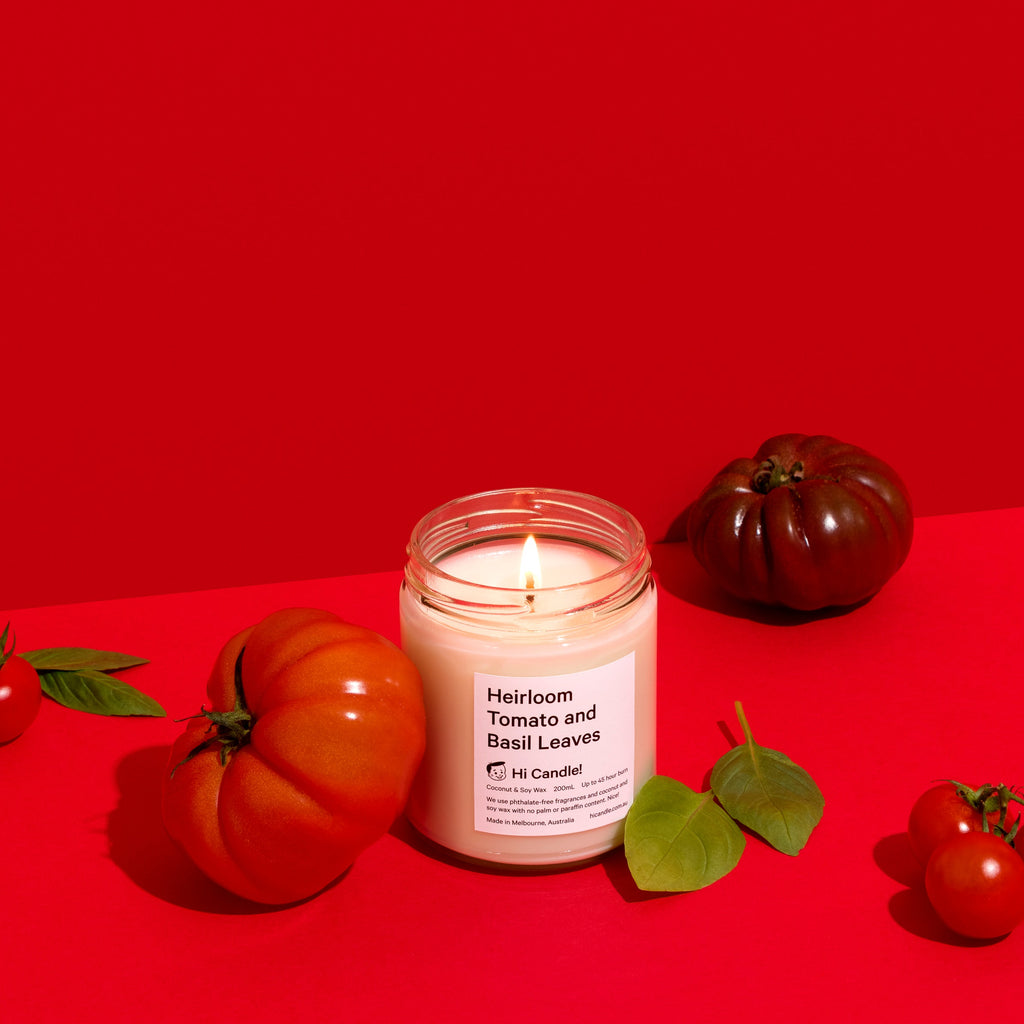 Candle with tomatoes and leaves on a red background