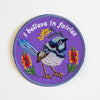 Iron-on patch with a bird design and 'I believe in fairies' text on a white background. 