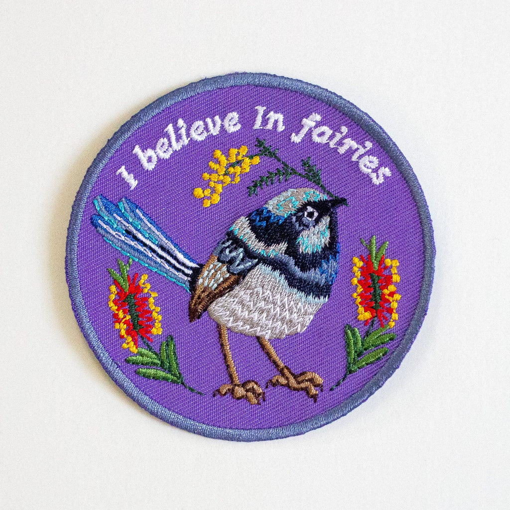 Iron-on patch with a bird design and 'I believe in fairies' text on a white background. 