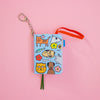 Small book-shaped keychain with animal illustrations on a pink background