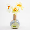 Vase with a face design holding flowers on a white background