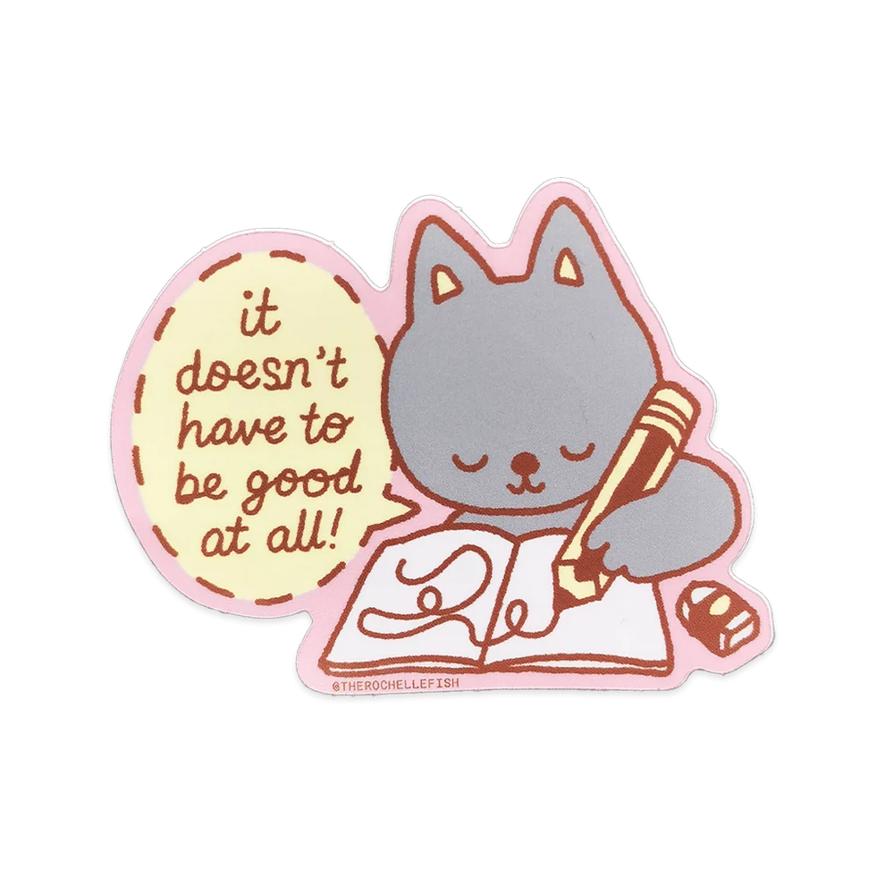 A die-cut sticker featuring a cute grey cartoon cat reading a book and writing in a pencil, with a pink speech bubble that says, 'it doesn't have to be good at all!'.