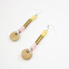 Pair of earrings with brass, ceramic, and fabric components on a white background