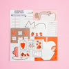 A flat-lay product shot of a 'Journaling Paper Pack' featuring various themed paper sheets with cute illustrations like apples, leaves, and flowers, set against a solid pink background.