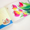 Open book with colourful illustrations of flowers and a boat on a white background