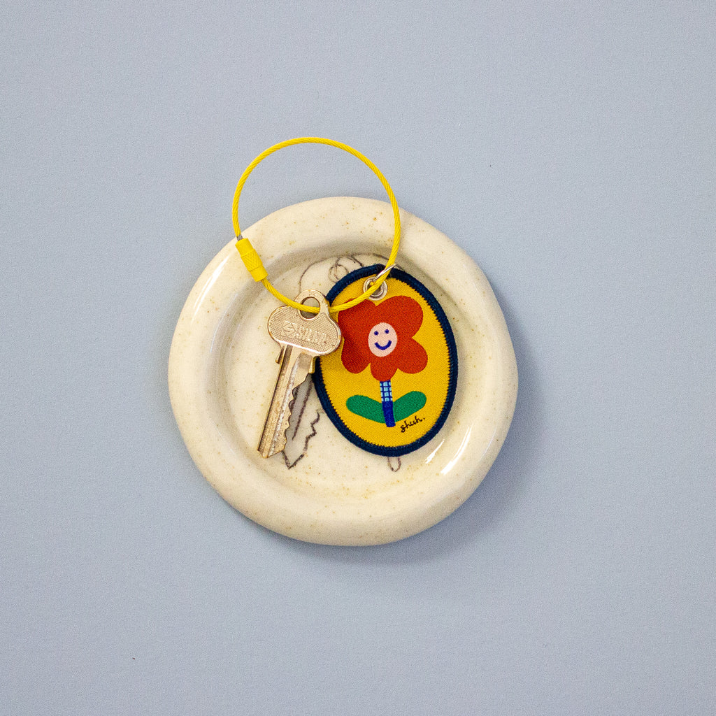 Decorative keychain with a cartoon flower design on a grey background