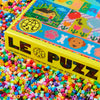 LE PUZZ box with colourful beads scattered around