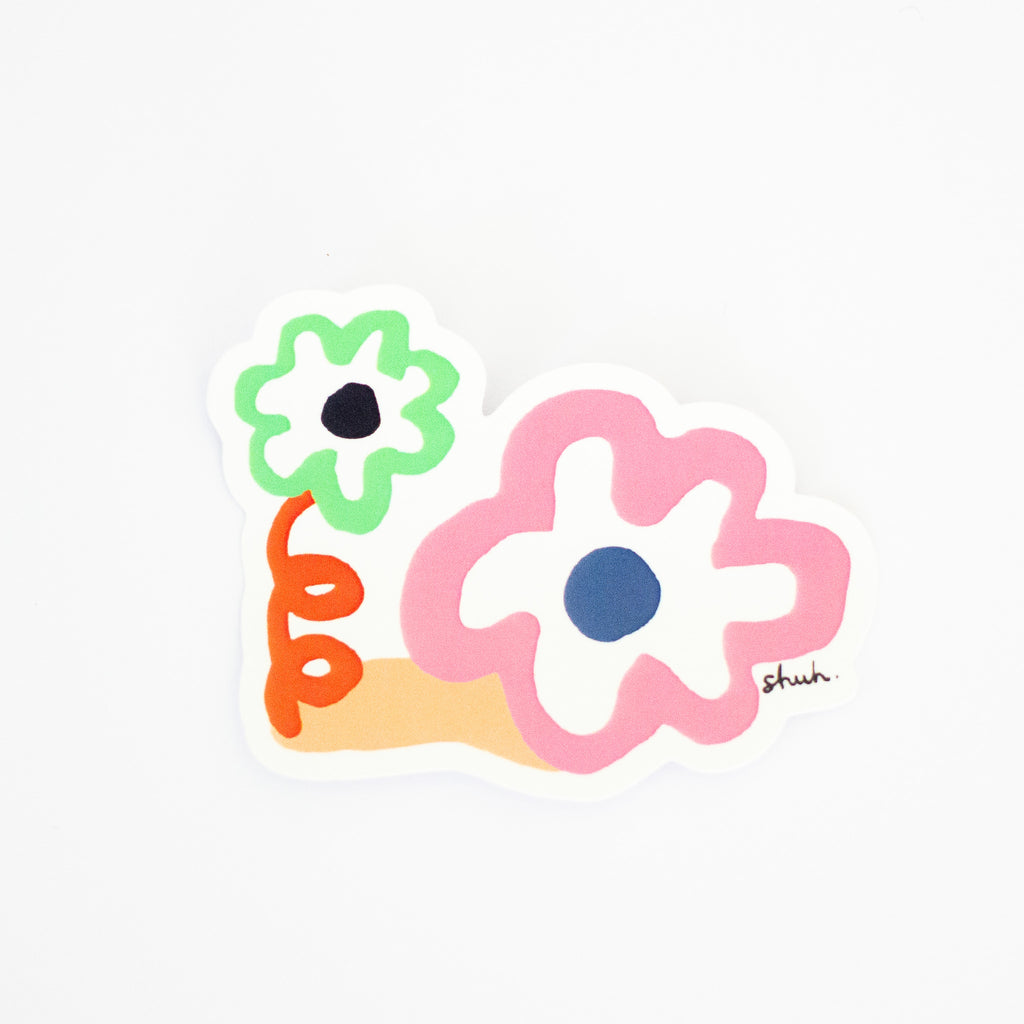 The kindness sticker, two flowers. One with twirly orange stem, and one large pink flower. 